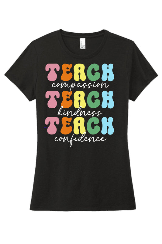 A black t-shirt featuring vibrant, colorful text that reads "Teach compassion, Teach kindness, Teach confidence," set against a black background.